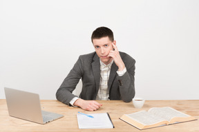 Pensive young teacher sitting at the table