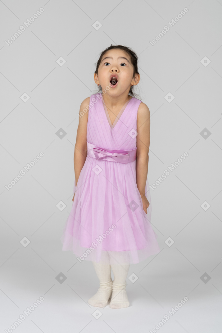 핑크 드레스를 입은 어린 소녀가 놀라서 서 있다