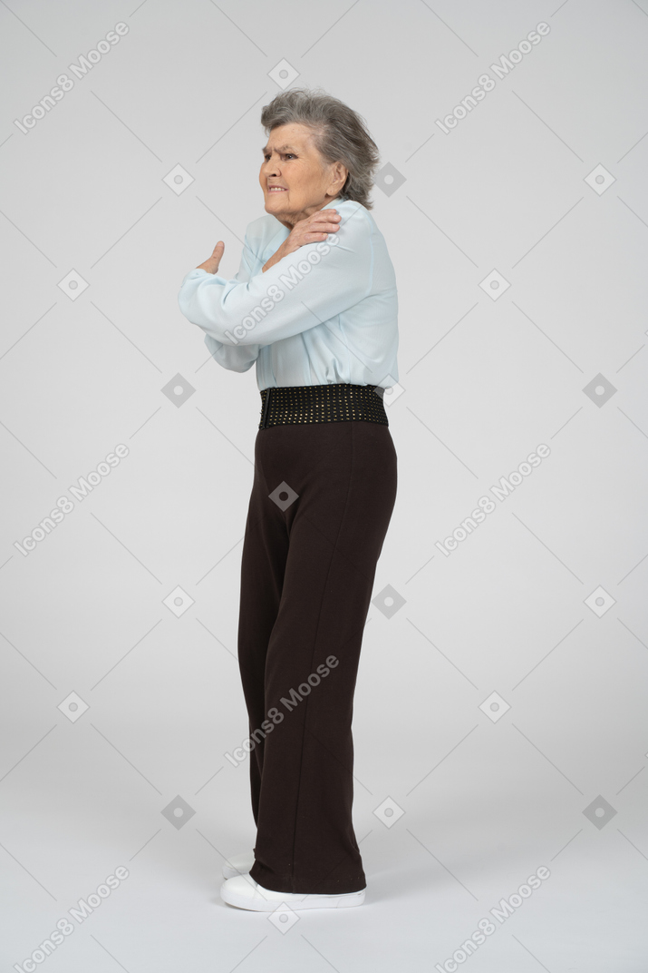 Elderly woman standing and hugging herself