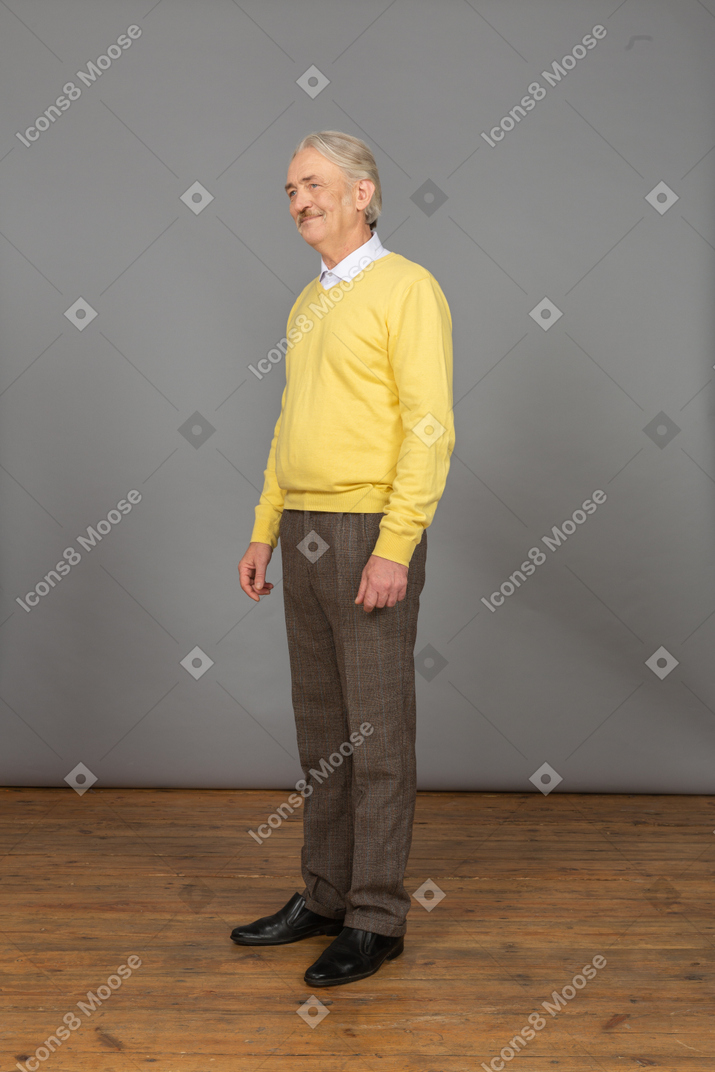 노란색 스웨터에 쾌활한 노인의 3/4보기 웃고 옆으로 바라보고