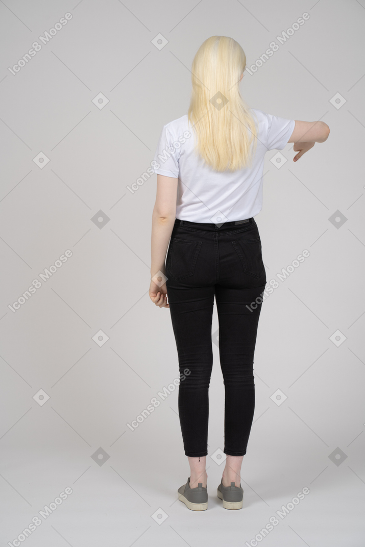 Молодая девушка стоит спиной к камере с опущенными пальцами
