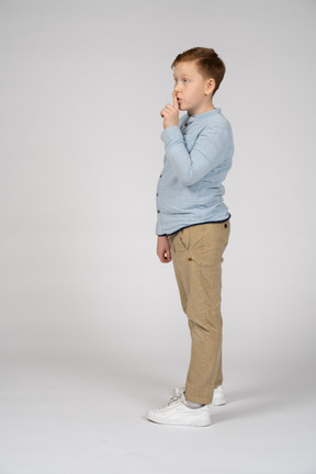 Side view of a boy making shhh gesture