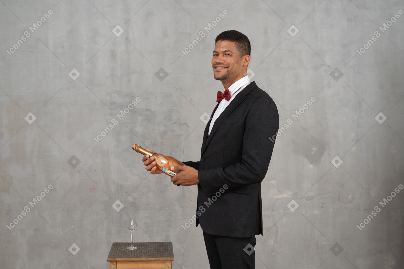 Joyful man standing and holding a bottle of champagne