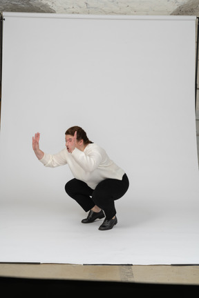 Side view of a plump woman in casual clothes squatting