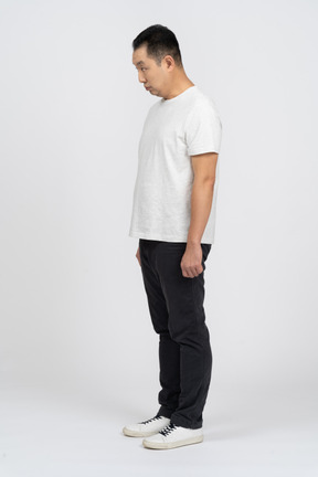 Man in casual clothes standing still and bending head down