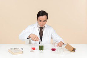 An asian scientist in a white coat working on a chemical experiment