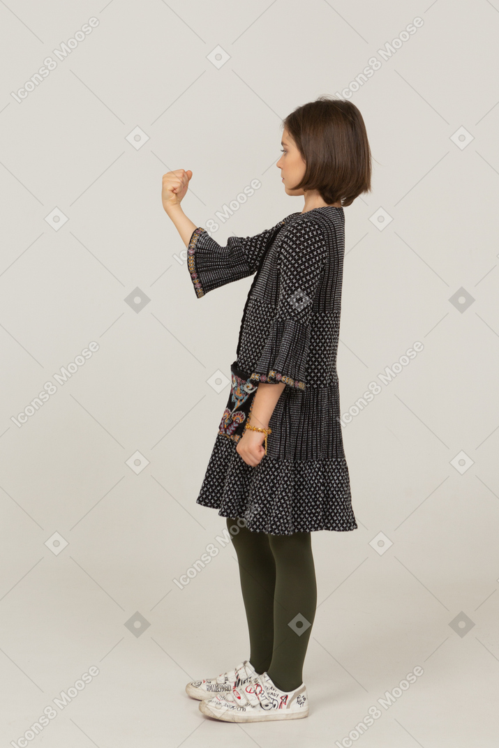 Side view of a little girl in dress clenching fist