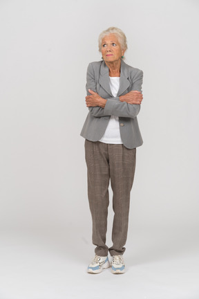 Vista frontale di una vecchia signora in abito in piedi con le braccia incrociate