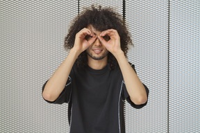 A man with afro hair making binoculars with his hands