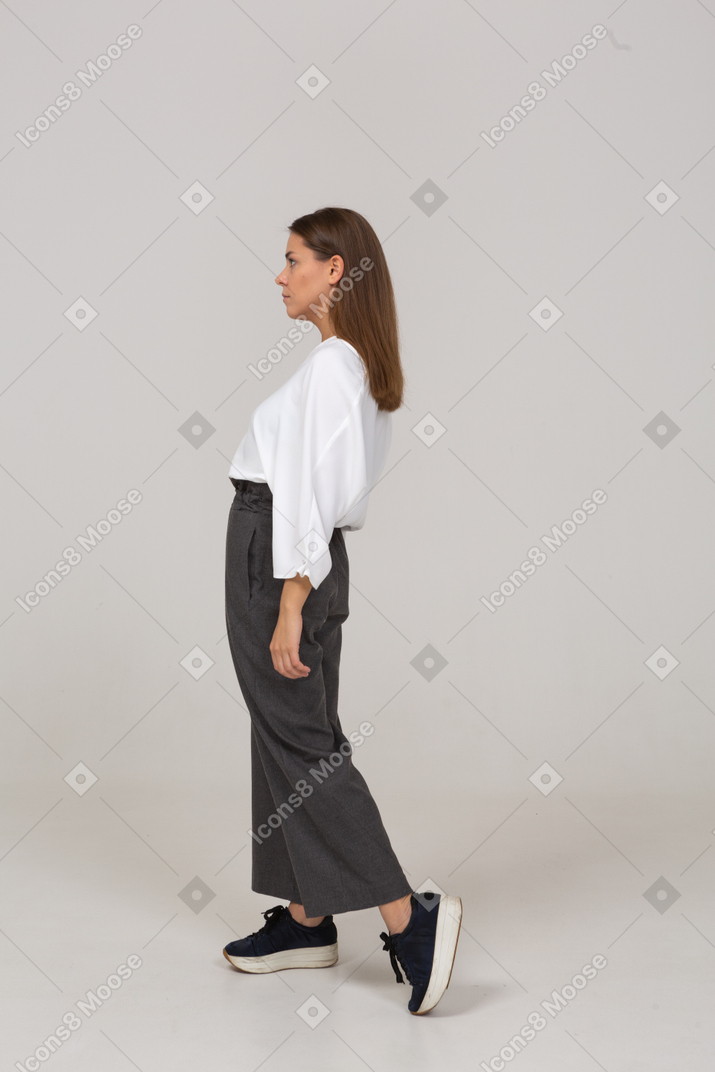Vista lateral de uma jovem com roupa de escritório dando um passo