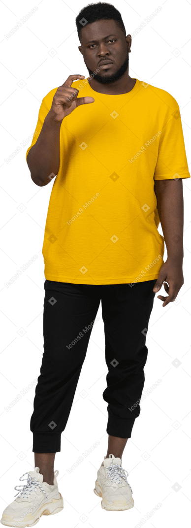 Vorderansicht eines jungen dunkelhäutigen mannes in gelbem t-shirt, das die größe von etwas zeigt