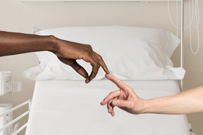 Two hands reaching for each other on a bed