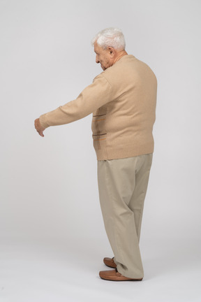 Вид сбоку на старика в повседневной одежде, стоящего с протянутыми руками