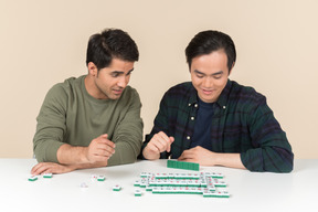 Interracial friends sitting at the table and playing board game