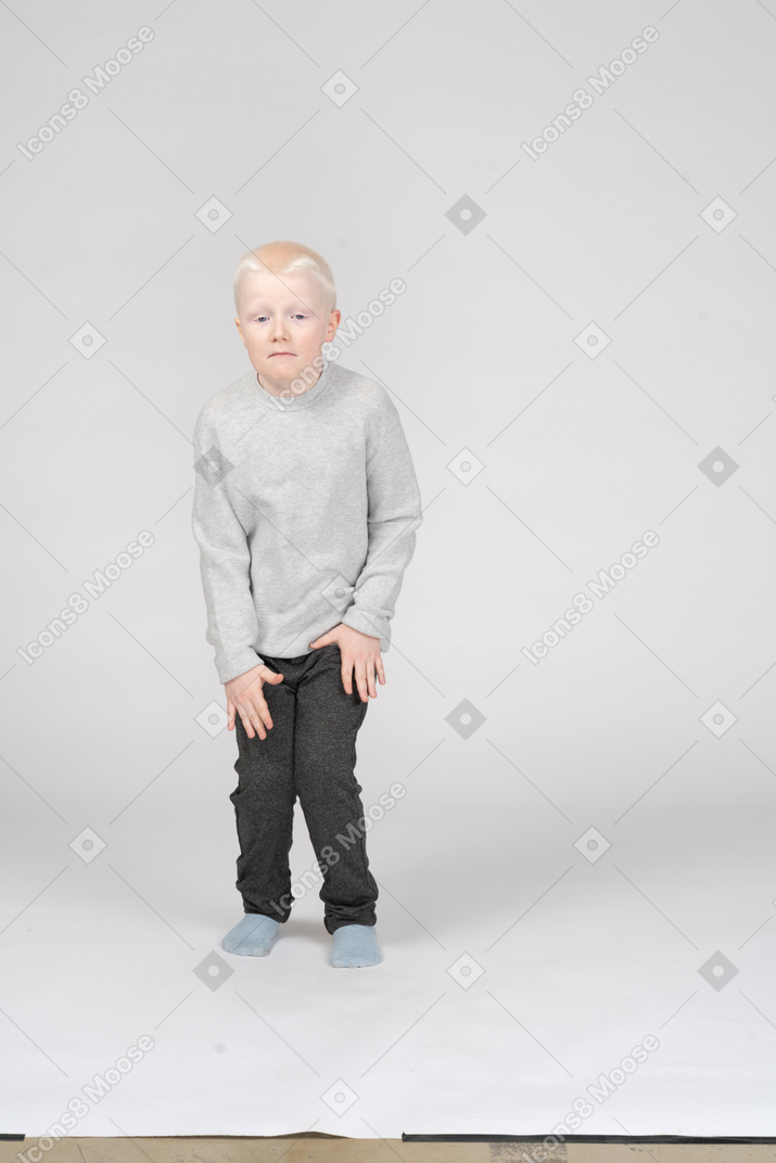 Vista frontal de um menino agachado ligeiramente