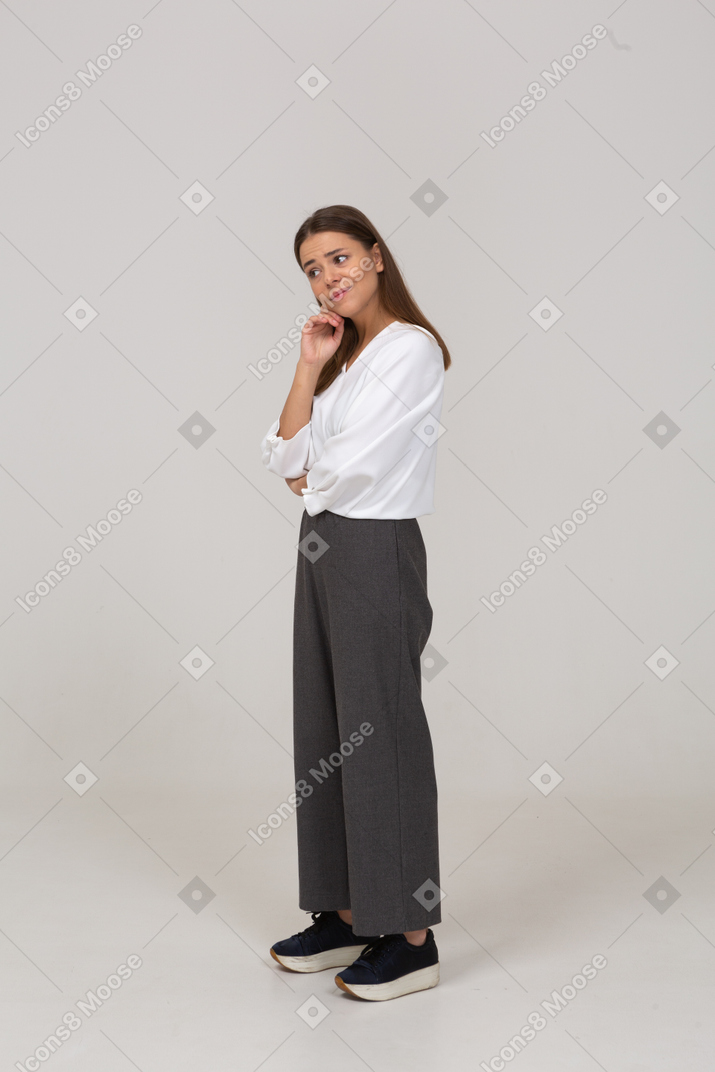 Vista di tre quarti di una giovane donna premurosa in abiti da ufficio che tocca il collo