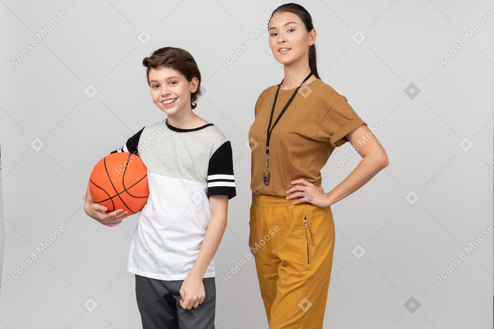 Professor de educação física em pé ao lado do aluno que está segurando uma bola de basquete