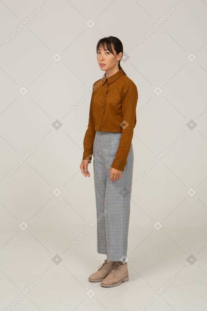 Three-quarter view of a young asian female in breeches and blouse looking at camera