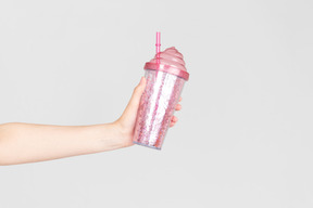 Female hand holding pink plastic cup