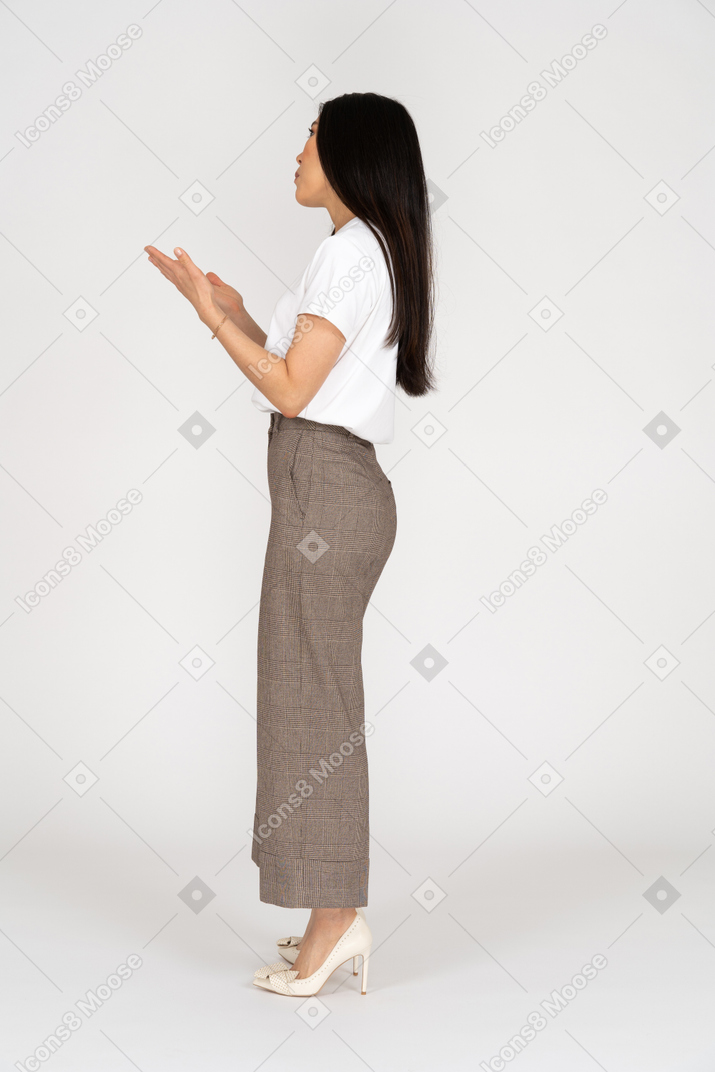 Vue latérale d'une jeune femme gesticulant en culotte et t-shirt expliquant quelque chose