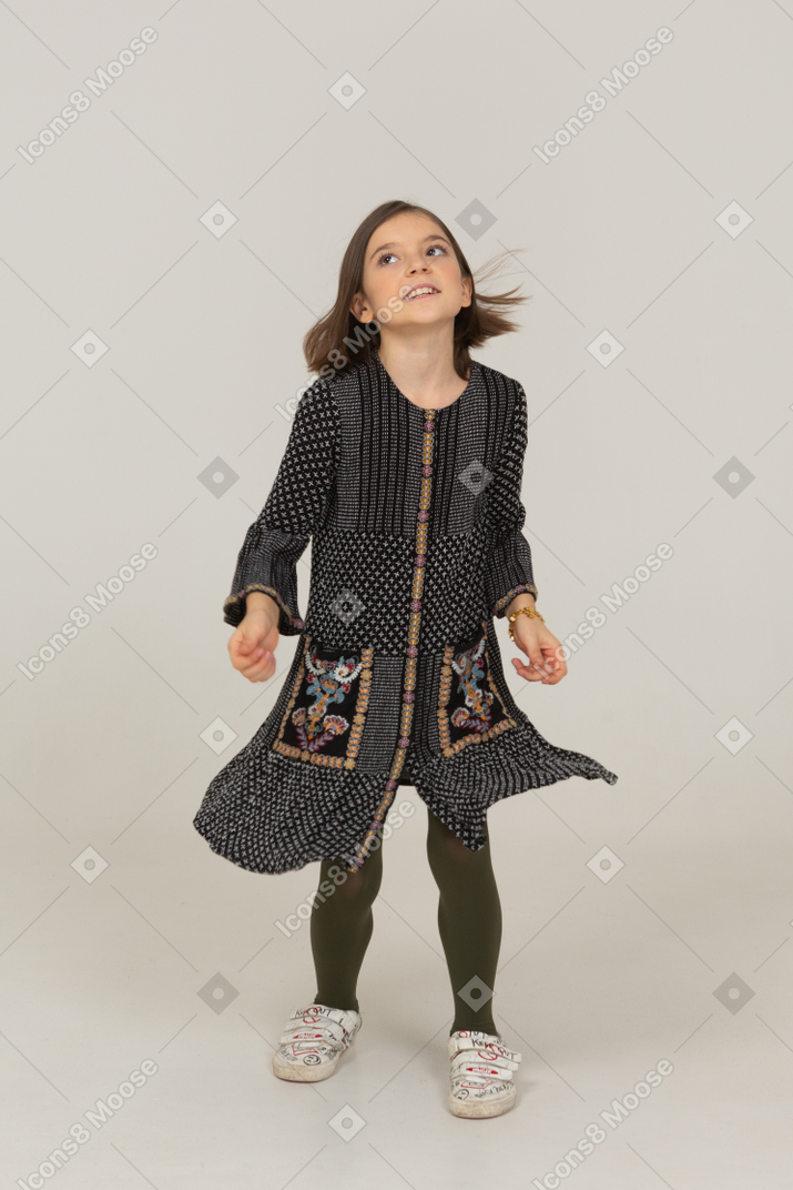 一个穿着裙子抬头的小女孩的前视图