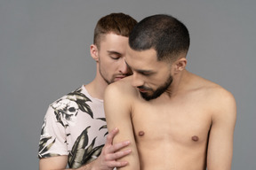 Close-up of a young caucasian man kissing shoulder of his shirtless partner