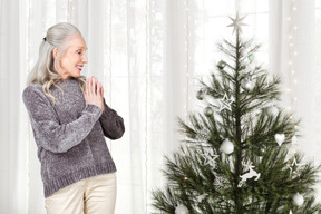 Mujer mayor feliz de ver el árbol de navidad decorado