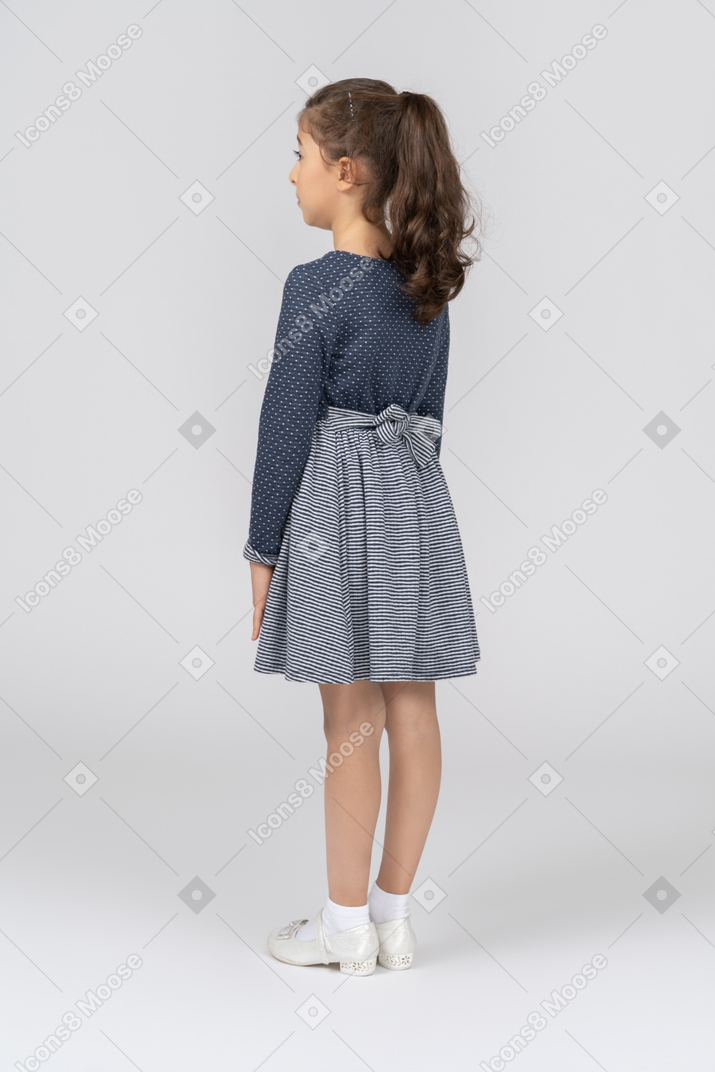 A girl with a ponytail standing with her back to camera