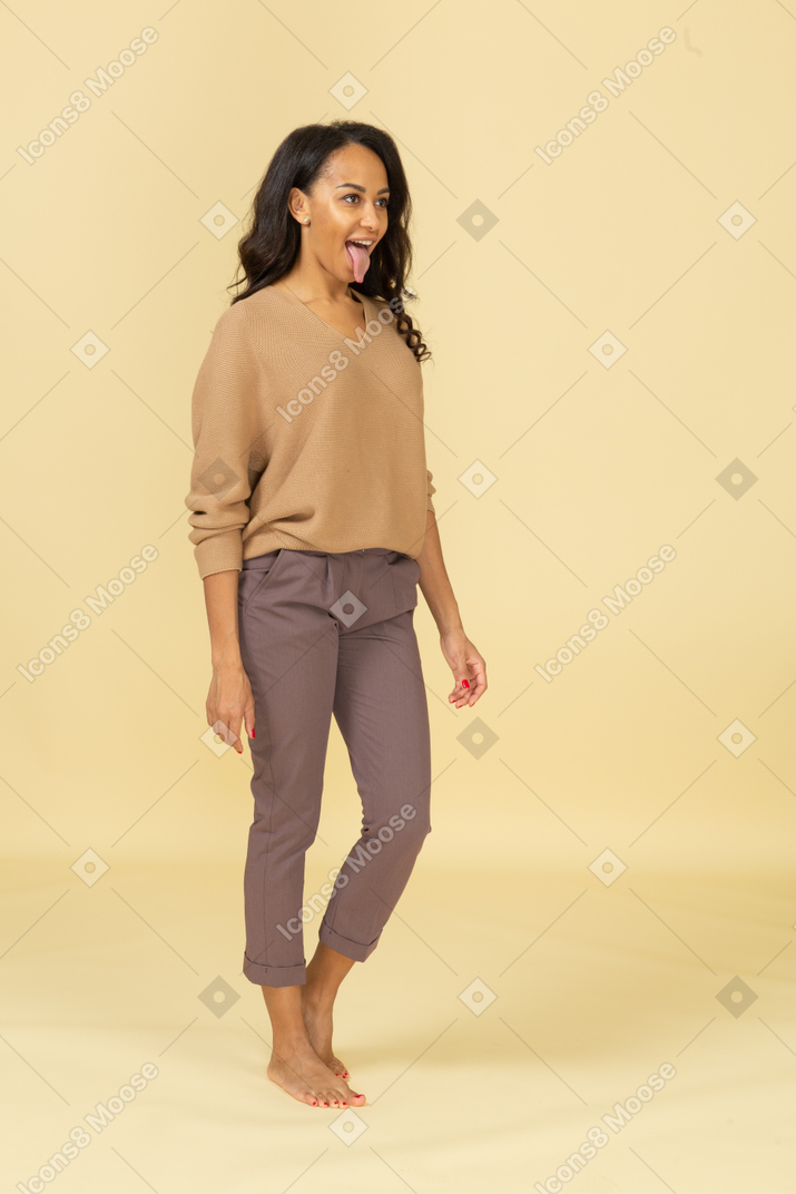 Three-quarter view of a young female in casual clothes showing tongue