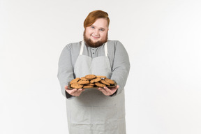 Um padeiro gordo sorridente oferecendo biscoitos