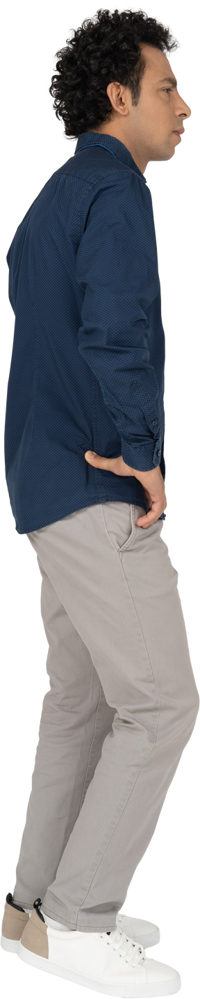 Vista lateral de um homem com roupas casuais, posando com as mãos na cintura