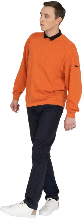 オレンジ色のスウェットシャツを歩いている若い男