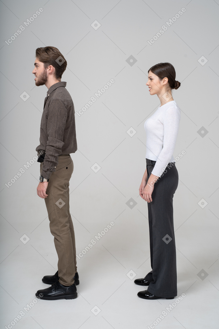 Side view of a young couple in office clothing clenching teeth