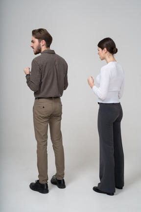 Three-quarter back view of a furious couple in office clothing clenching fists