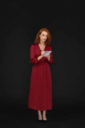 Bela dama vestida de vermelho e escrevendo em um bloco de notas