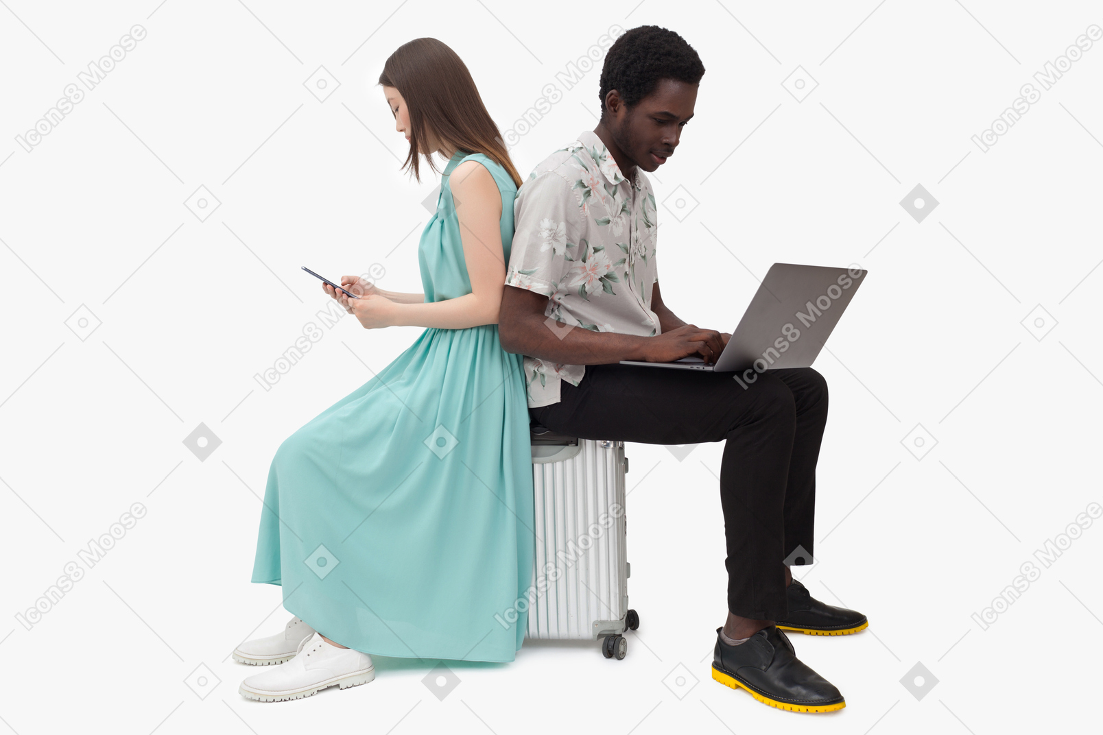 Couple interracial assis sur une valise et utilisant des gadjets