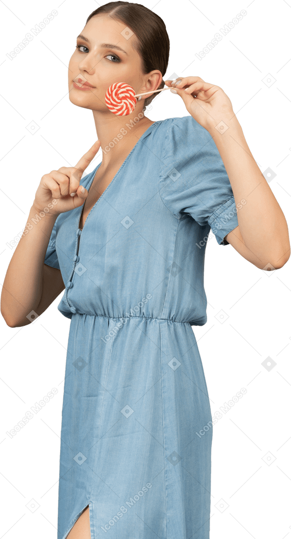 Vue de trois quarts d'une jeune femme en robe bleue tenant une sucette