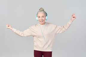 Jovencita alegre con auriculares bailando al ritmo de la música