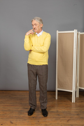 Front view of a thoughtful old man pointing his cheek