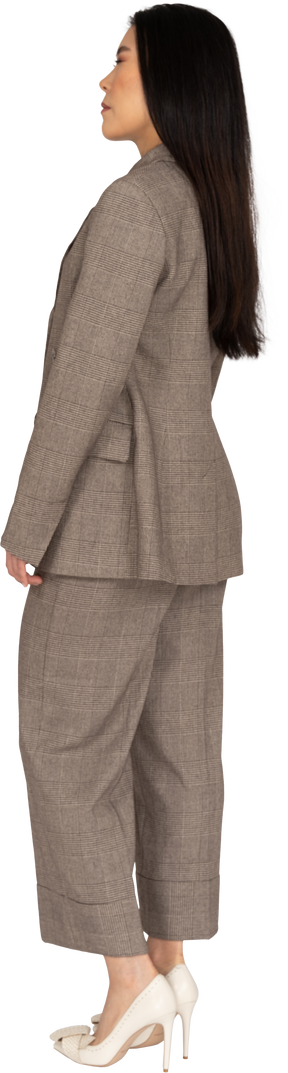 Вид сзади в три четверти молодой леди в коричневом деловом костюме, закрывающей глаза