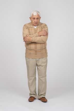Vista frontal de un anciano con ropa informal abrazándose a sí mismo