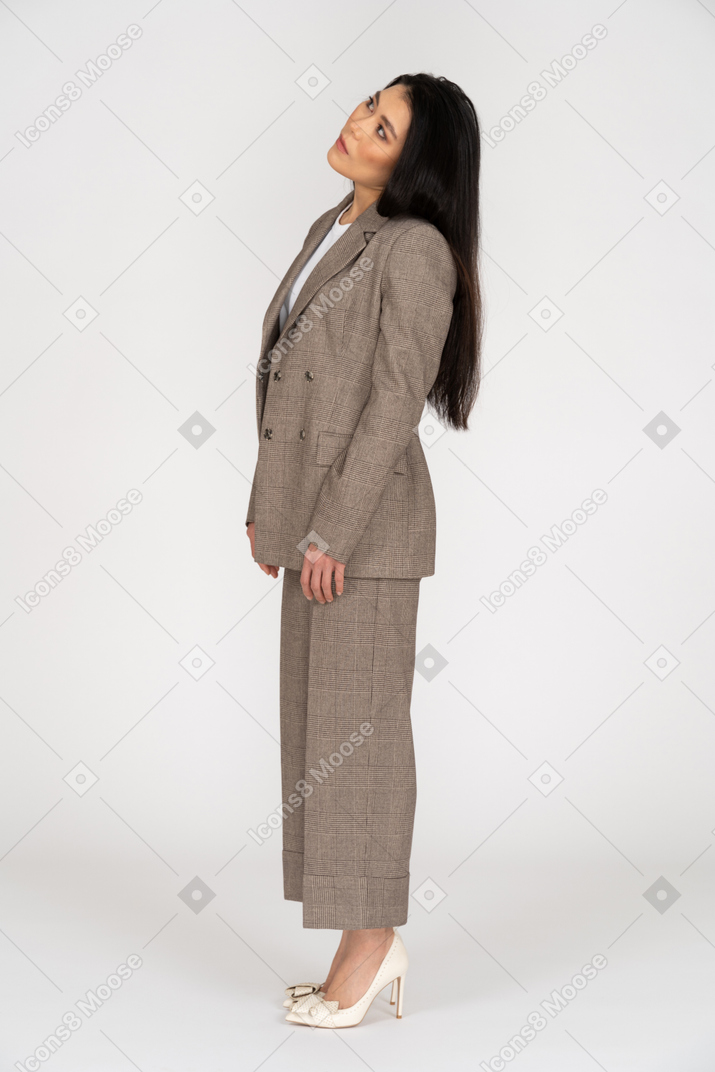 Side view of a young lady in brown business suit looking aside while tilting head
