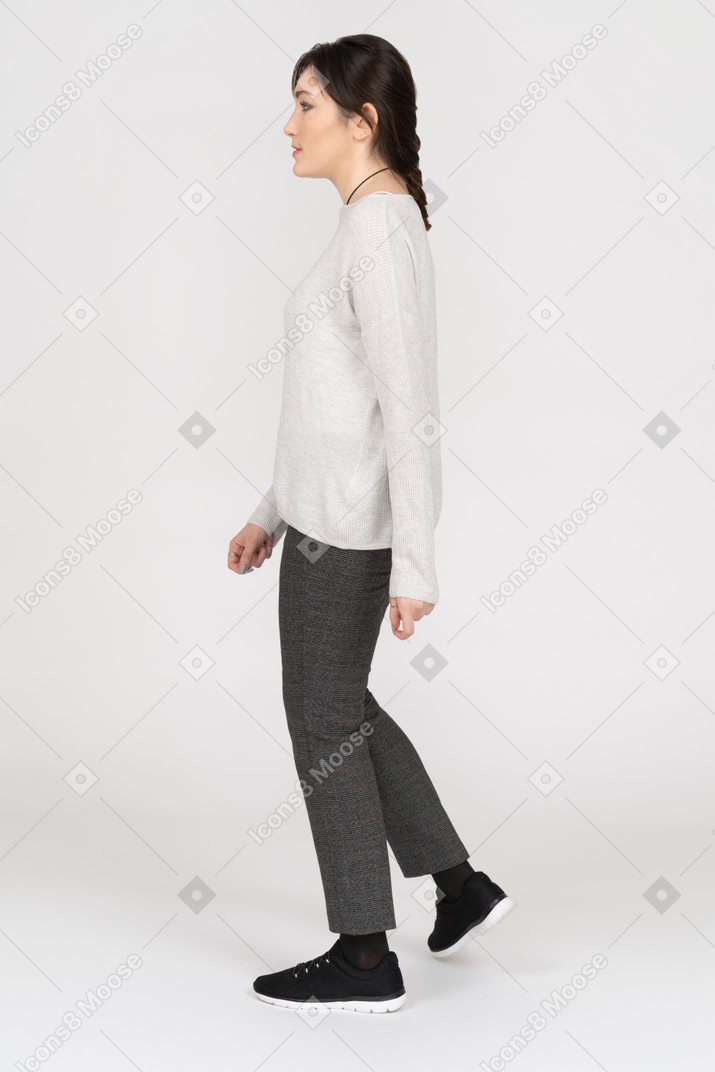 Sottile giovane donna bruna che cammina lateralmente