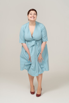Vista frontal de una mujer feliz en vestido azul mirando a la cámara