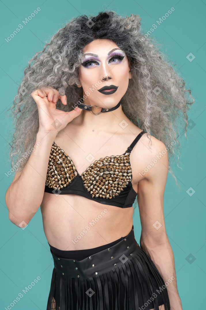 Drag queen in studded bra pulling on their choker