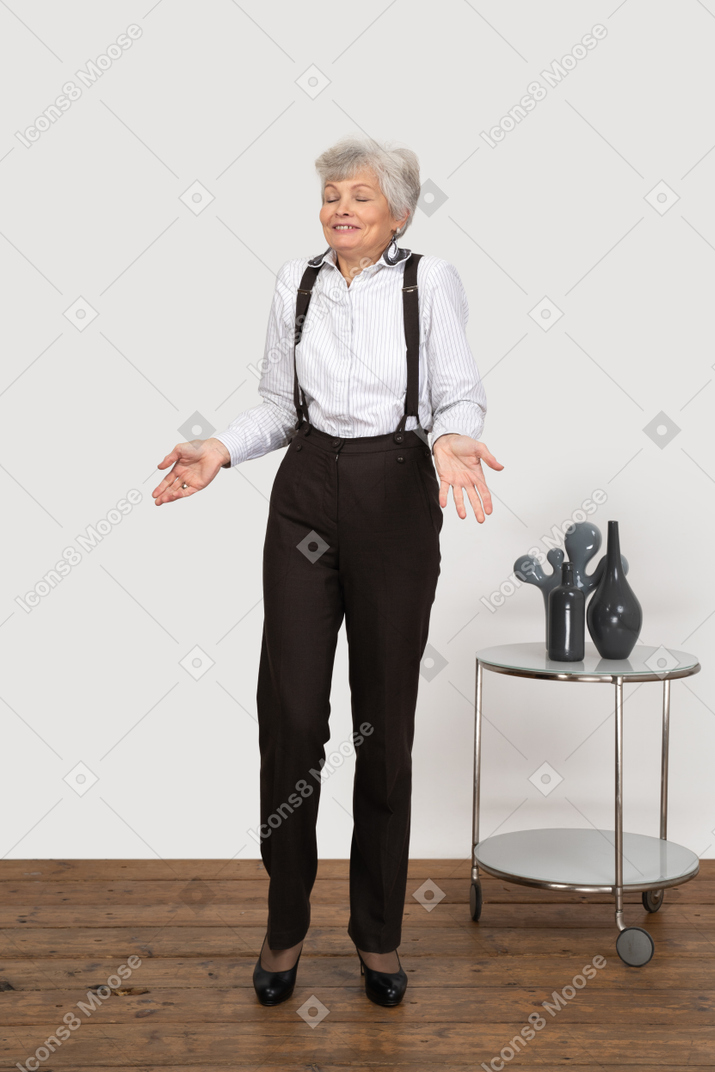 Vista frontale di una vecchia signora sorridente gesticolante in piedi con gli occhi chiusi