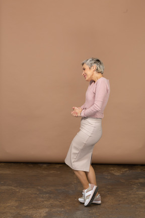 Вид сбоку счастливой женщины в повседневной одежде, позирующей на одной ноге