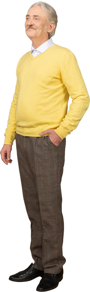 Вид в три четверти довольного старика в желтом пуловере, который кладет руку в карман и смотрит в сторону