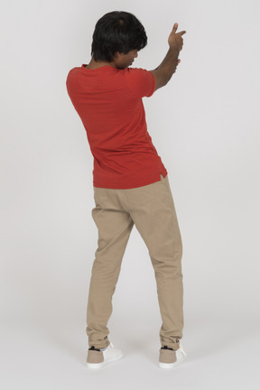 Back view of young man pointing with finger gun