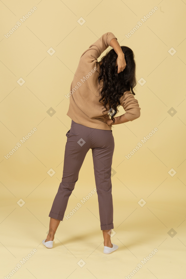 Back view of a dark-skinned young female touching hair